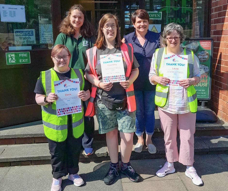 SHAX volunteers outside the charity shop holding thank-you certificates